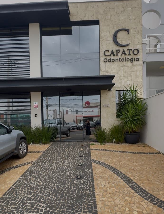 Vista externa da clínica odontológica com destaque para a entrada e o nome.